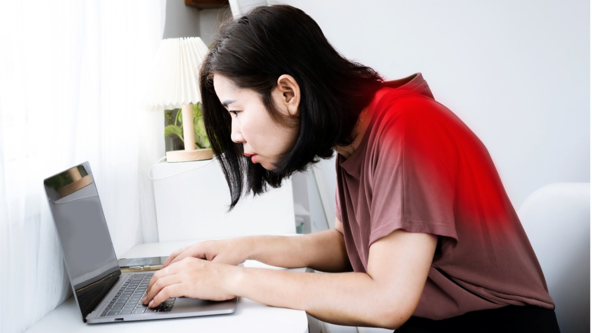 A woman working at her computer with a slouched posture puts her at risk of developing a condition known as neck hump