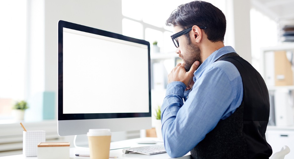 Office worker sitting at his desk, with his monitor set at the correct height