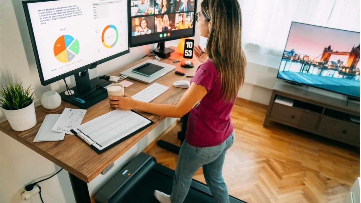 A woman utilising an under desk treadmill while working from home