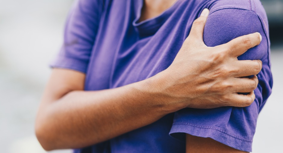 Young female holding her shoulder suffering from sharp pain