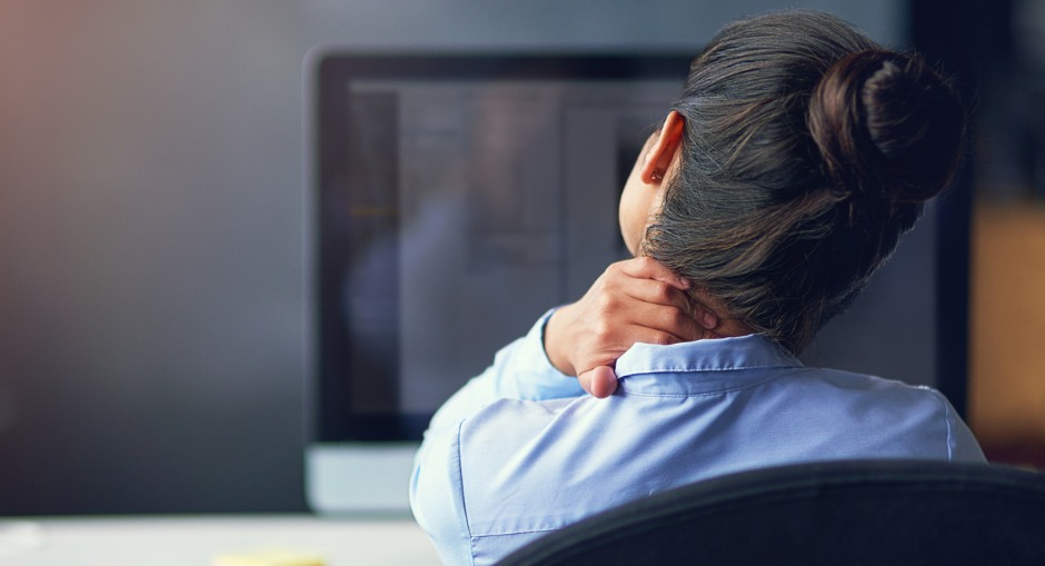 Office worker holding neck suffering from muscle pain, while working desk.