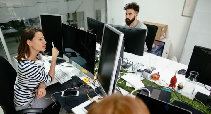 Woman in the office working from a poorly designed ergonomic monitor setup.