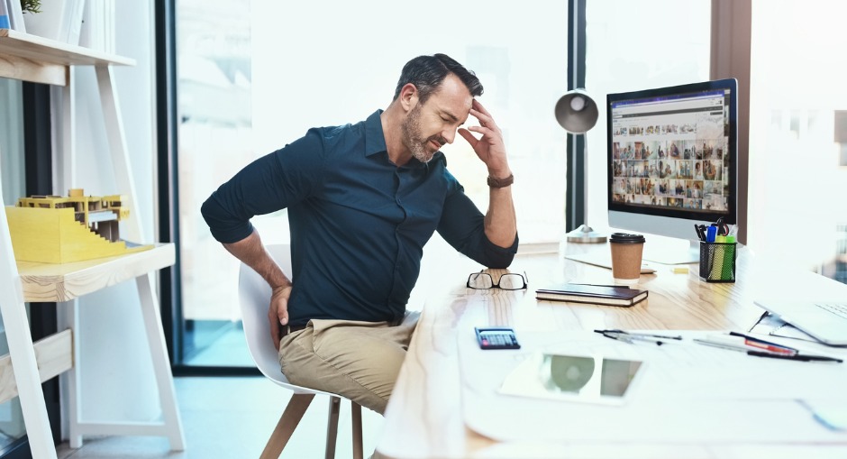 Male office worker in pain from sitting on a standard office chair