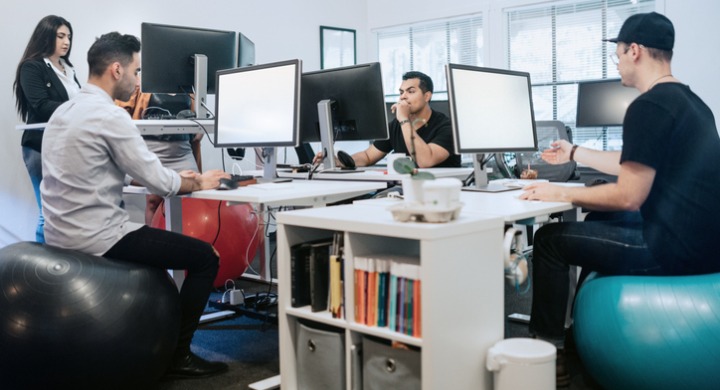 An office department using exercise balls as office chairs while working at their desks.