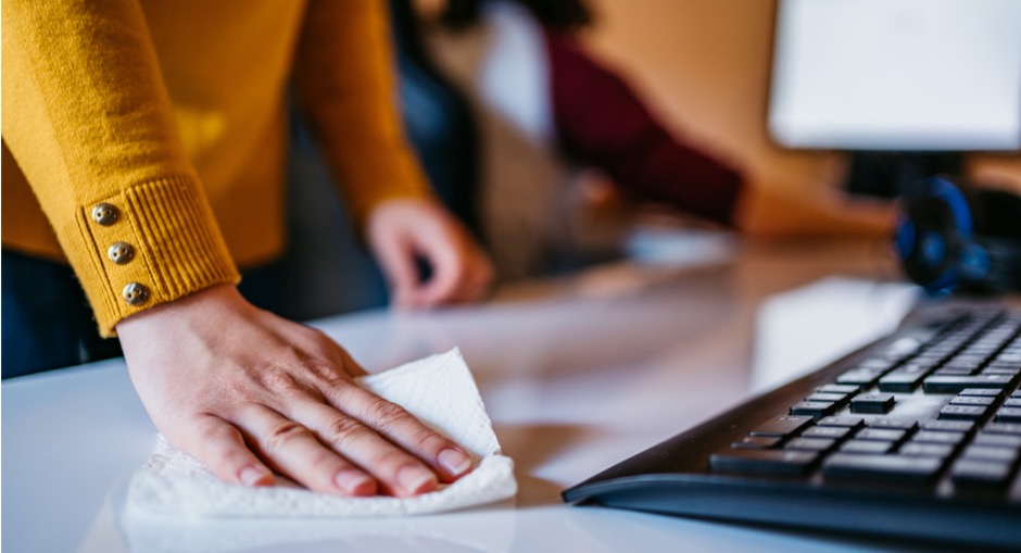 Female office worker disinfecting her workstation