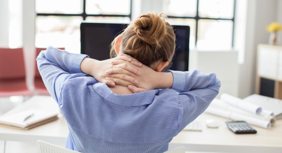 Office worker holding her neck in pain after sitting all day on a uncomfortable regular office chair 