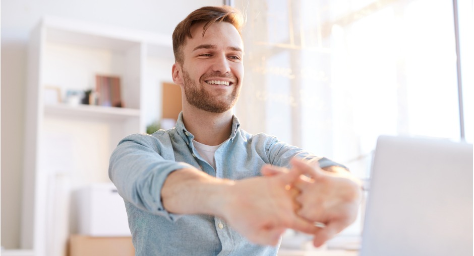 Man doing stretches at his desk to improve circulation in his hands during the work day.