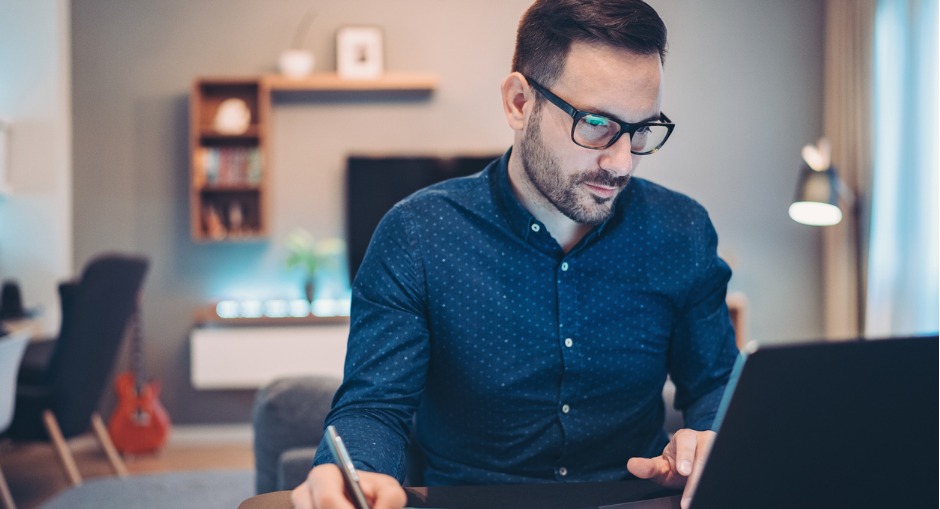 Man sitting at his desk at home budgeting for an upgrade to his workstation setup.