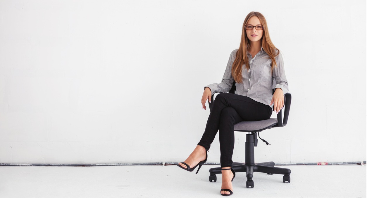 A business woman sitting in an ergonomic office chair against a white background