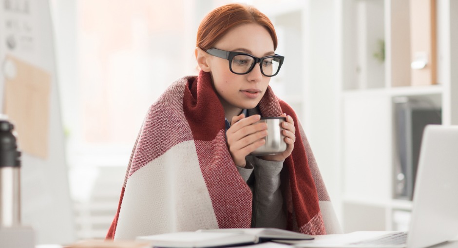  Young female office worker working in a cold of office space.