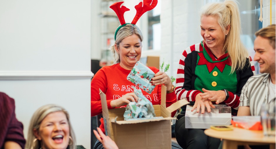 Office workers enjoying their Christmas party and exchanging Secret Santa gifts.