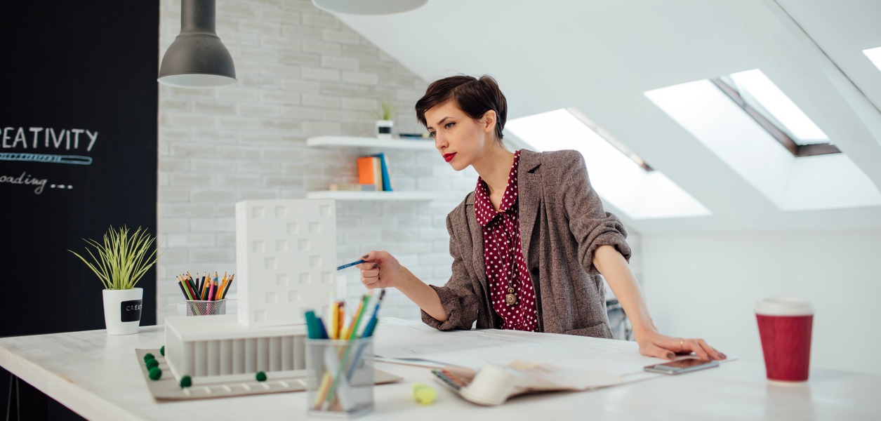 A stylish professional woman working standing up at her standing desk in a modern looking office