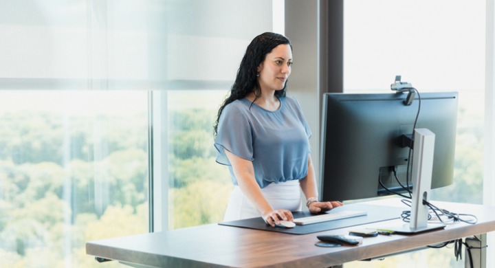 Woman practices good ergonomics while using her computer at work in order to avoid issues associated with static posture.