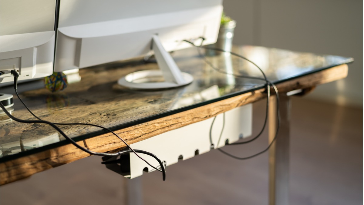 the back of a desktop computer sitting on a desk with the cords hanging 