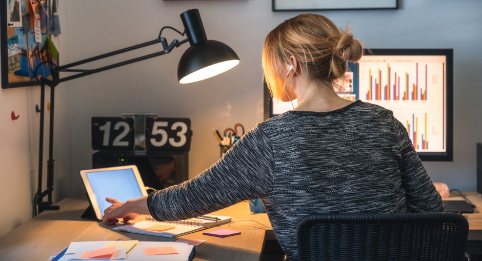 Woman working on a computer and digital tablet in her home office.